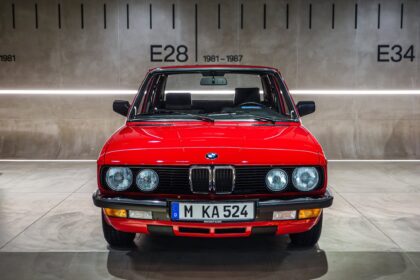 BMW roșu fotografiat frontal în fața panoului E28, 1981-1987, la BMW Museum München.