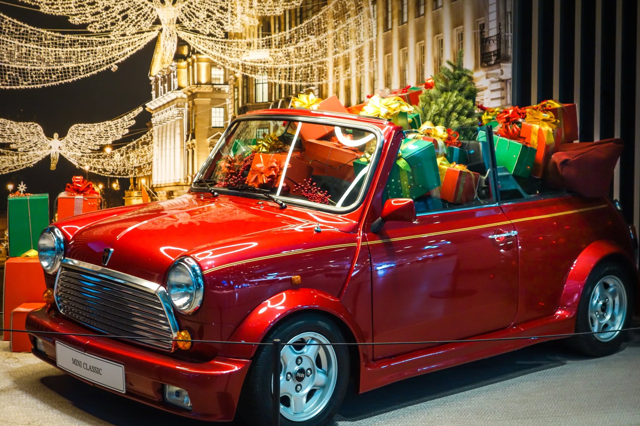 Mini Cabriolet clasic roșu cu pachete decorative și lumini de sărbătoare